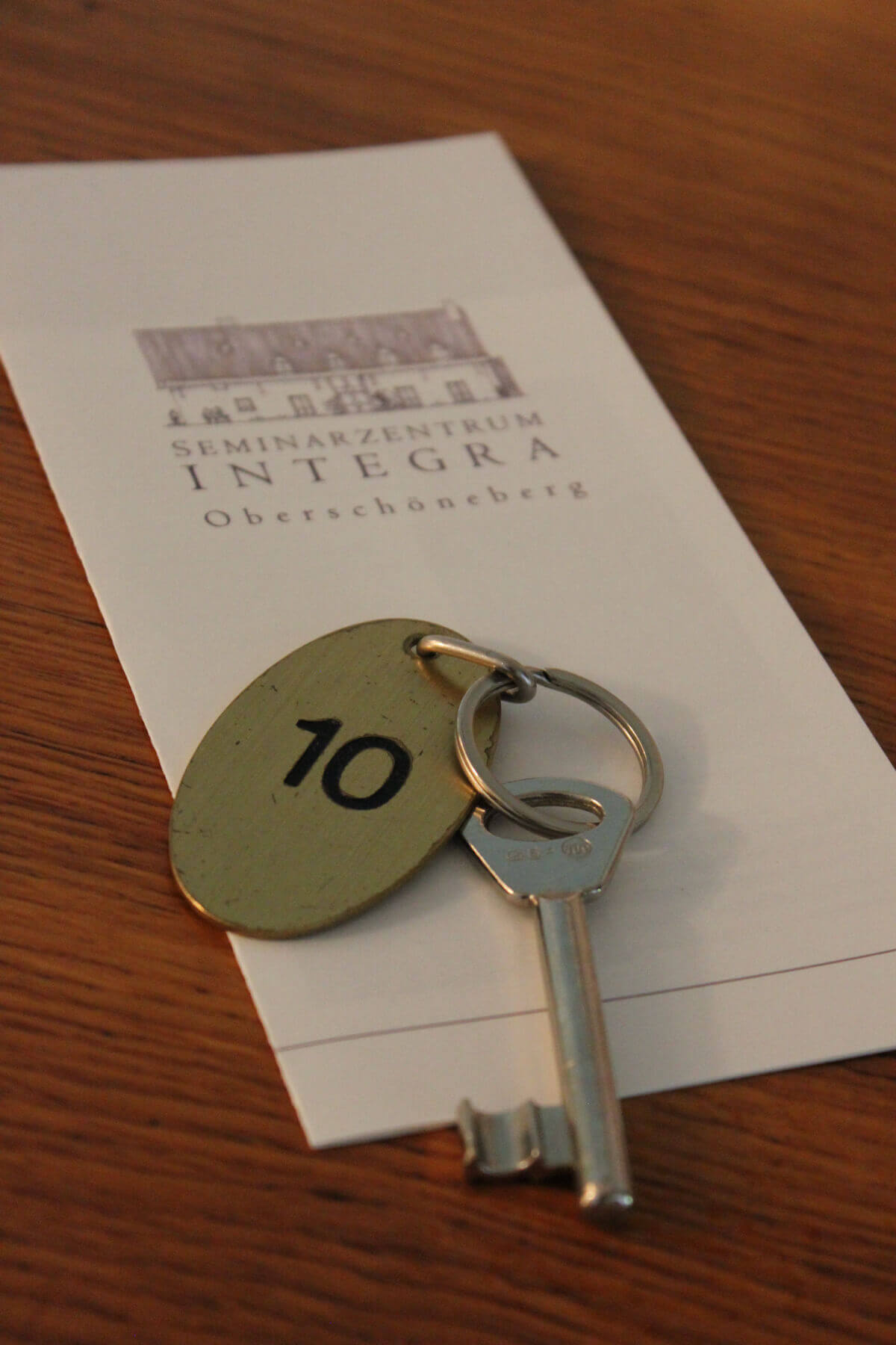 Ein Hotelschlüsse, auf dessen Anhänger die Zimmernummer 10 abgebildet ist. Der Schlüssel liegt auf einem Stück Papier.